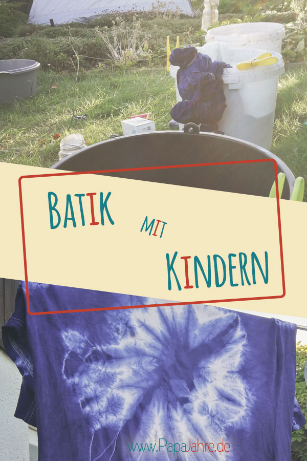 Titelbild - Batik mit Kindern. Mit ein paar Eimern im Garten, darin Kleidungsstücke und im unteren Teil des Bildes ein auf der Leine hängendes Shirt in Blau